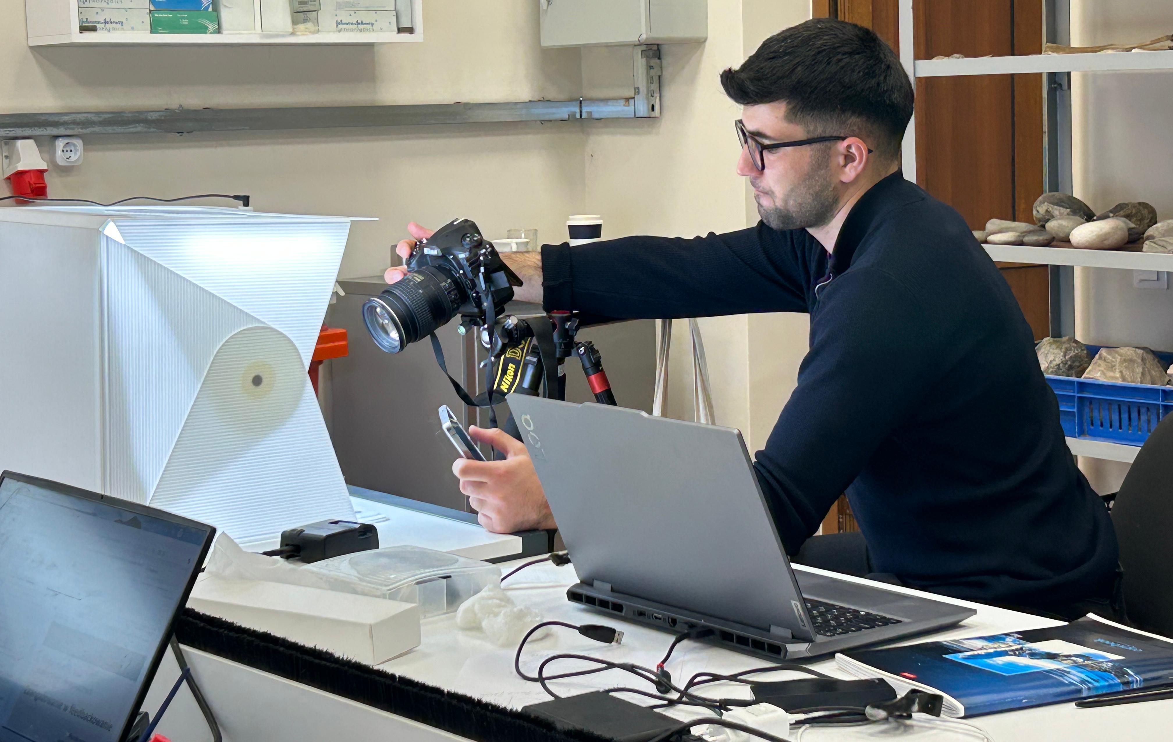 Azykh lab student taking photo of an artifact
